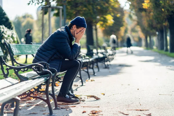 Jeune homme inquiet sur un banc pendant la journée d'automne Images De Stock Libres De Droits