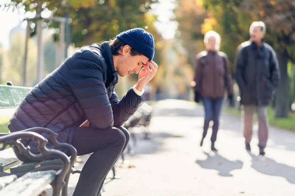 Worried young man on a bench during autumn day Stock Picture