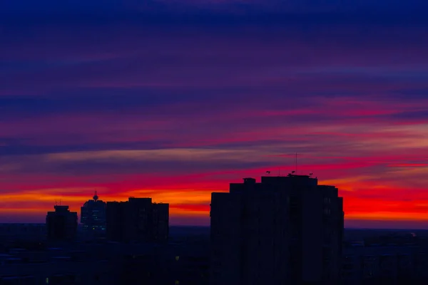 Early winter morning over the city. Red-blue bright sky. The sun has not yet risen. The city begins to wake up