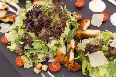 Sezar salatası peynir ve domates siyah seramik plaka üzerinde