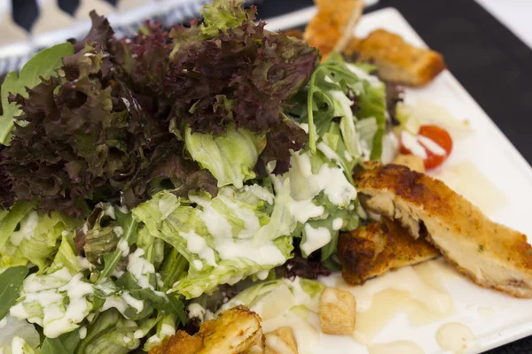 Sezar salatası peynir ve domates siyah seramik plaka üzerinde