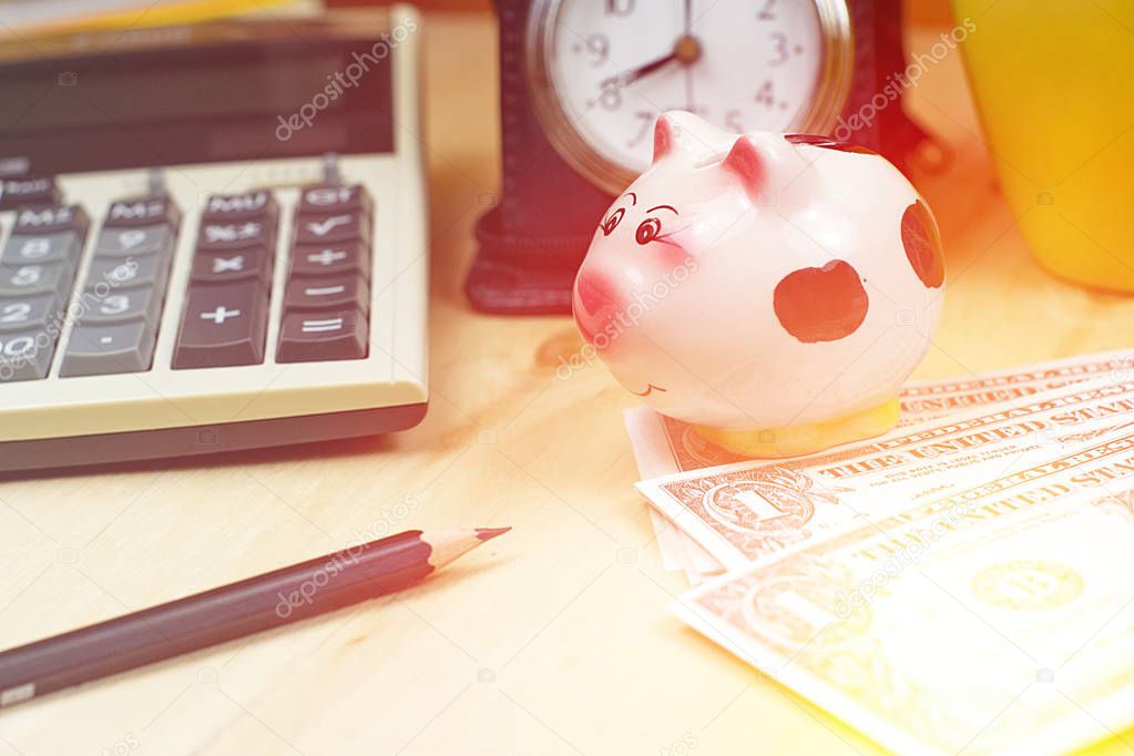 Small piggy bank and financial calculator, Piles of  US dollar b