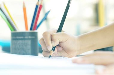 Küçük çocuğun el bir şey beyaz kağıt üzerine çizim.