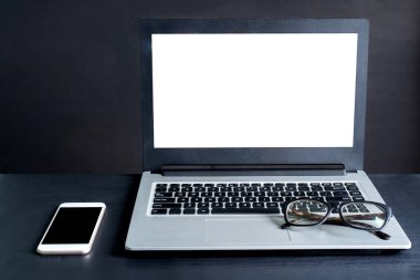 Laptop, akıllı telefon, gözlük, siyah arka planlı siyah ahşap masa.