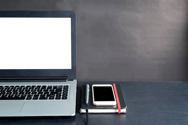 Laptop, akıllı telefon, defter, kalem, siyah arka planlı siyah ahşap masa