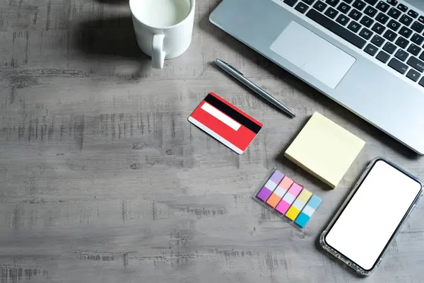 Bilgisayarın üst görüntüsü, akıllı telefon, kredi kartı, bir fincan süt, kağıt not, kalem, ahşap masa üzerinde iş, ticaret, finans, eğitim kavramı ve tasarım