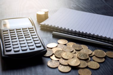 Altın sikkeleri, hesap makinesini, kalemi, defteri siyah masaya kapat. İş, finans, pazarlama, e-ticaret konsepti ve tasarım