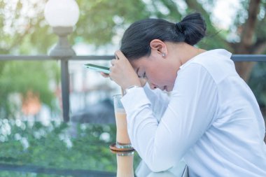 Oturup su içen bir kadın, aşağı bakıyor ve bir şeyler düşünüyor.