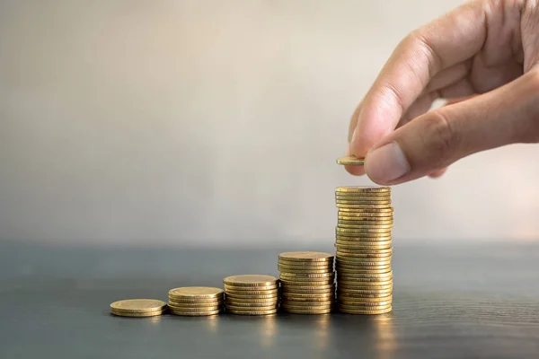 Monedas de oro apiladas a mano sobre mesa de madera negra. Negocios, finanzas, marketing, concepto y diseño de comercio electrónico Imagen De Stock