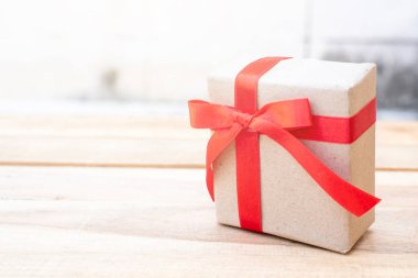 Hediye kutusunu kapat. Tahta masanın üzerinde hediye kutusuyla kırmızı kurdele, fotokopi alanı ile paketlenmiş klasik kutu.