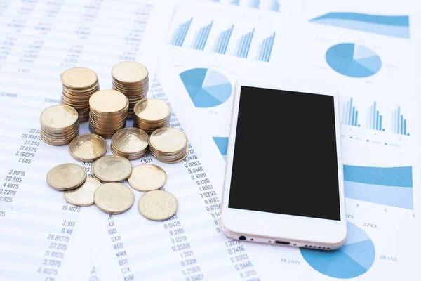 Stack of coins and smartphone on blue pastel chart paper. Business, finance, marketing, e-commerce concept and design.