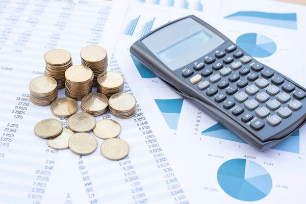 Stack of coins and calculator on blue pastel chart paper. Business, finance, marketing, e-commerce concept and design.