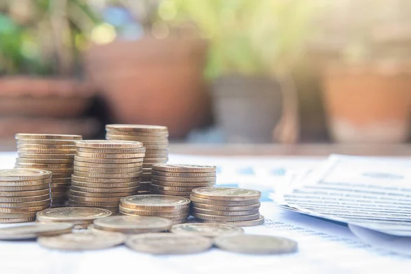 Stack of coins on blue pastel chart paper and blur nature background with sun light. Business, finance, marketing, e-commerce concept and design.