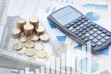 Double exposure  stack of coins and calculator on blue pastel chart paper and blur building background. Business, finance, marketing, e-commerce concept and design.