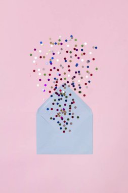 Yılbaşı kutlaması konsepti. Pembe arka planda mavi zarfta renkli konfeti