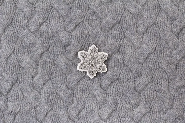 Textura šedé pleteniny zblízka s dřevěnou sněhovou vločkou — Stock fotografie