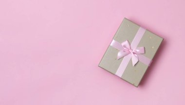 Yılbaşı yeni yıl şablonu. Pastel pembe kağıt arka planda güzel bir hediye kutusu.