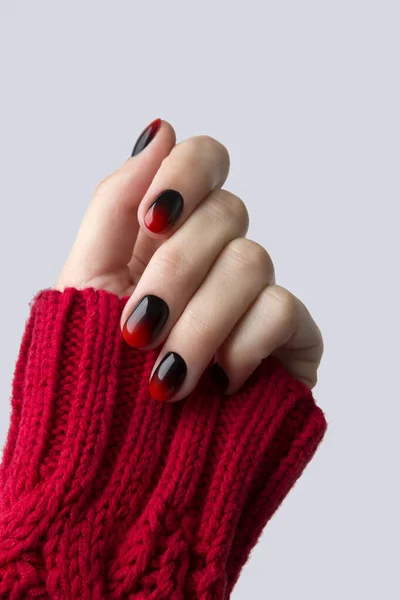 Female hand with red black ombre gradient nails in sweater — Stock Photo, Image