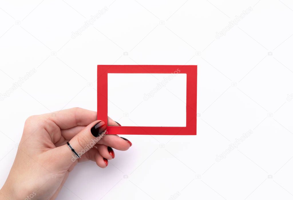 Womans hand with manicure holding red frame isolated on white background
