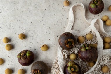 Düz kompozisyonda taze mangosteen ve longan meyveleri vardı.