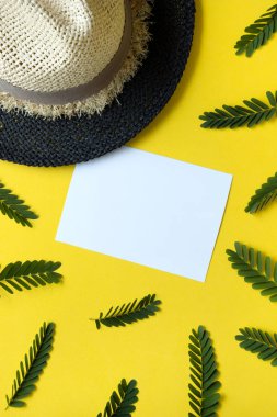 Yeşil dalları ve sarı arka planda hasır şapkası olan boş kartpostal.