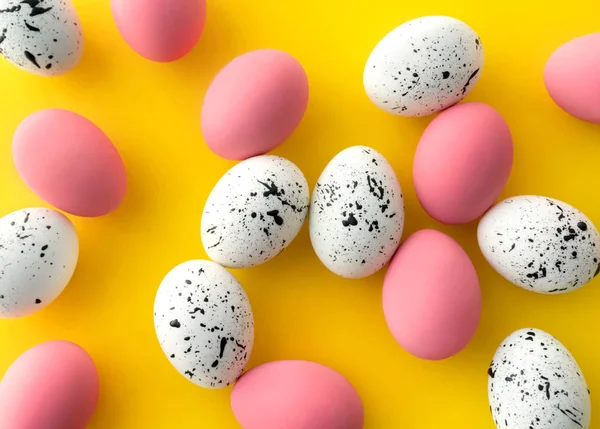 Vista superior plana de huevos blancos y rosados con diseños mínimos sobre fondo amarillo — Foto de Stock