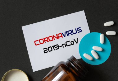 Kahverengi bir şişeden beyaz haplar dökülüyor.