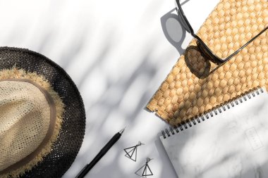 Moda güneş gözlükleri, planlamacı, şapka, arka planda palmiye yaprağı gölgesi olan küpeler.