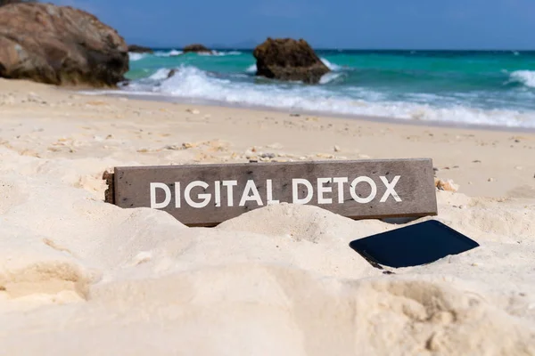 Old wooden sign with text digital detox on tropical beach. Rest from social media gadget and interne