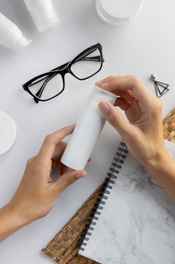 Kozmetik nemlendirici krem sürmüş kadın elleri. Beyaz masa arkasında minimalist tarzda fotokopi alanı var. Kadınsı güzellik blogu konsept şablonu