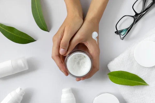 Women's hands apply cosmetic moisturizing cream lotion on white table. Natural cosmetics. Feminine beauty blog concept template
