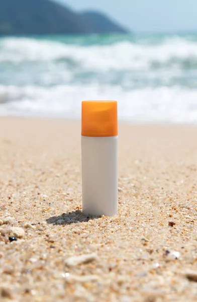 Bottle of sunscreen lotion on the sandy beach by the sea. Health skin care sun protection concept. Cosmetics with natural ingredients.
