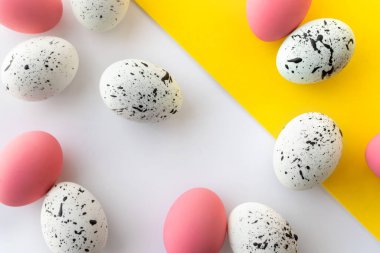 Beyaz ve sarı arka planda boyanmış yumurtalardan oluşan yaratıcı Paskalya düzeni. Düz görünüm kopyalama alanı.