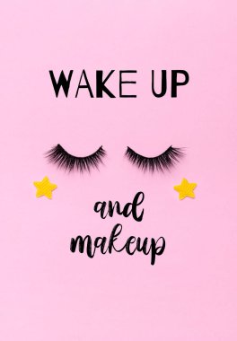 Greeting card with eyelashes and text: wake up and makeup. Closed eyes with stars on pink background.