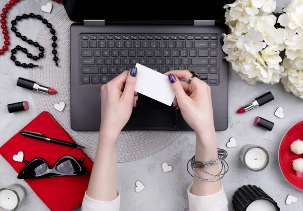 Güzel bakımlı bir kadının elleri ofis masasında tebrik kartı tutuyor. Güzellik blogcusu çevrimiçi alışveriş kavramı
