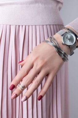 Gümüş mücevherleri ve aksesuarları olan kadın elleri. Minimum pembe bahar manikür tasarımlı bir kız. Moda güzellik konsepti