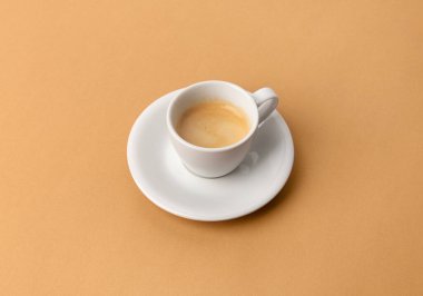 Bej masadaki beyaz bardakta espresso kahvesi. Pop art minimal düz, yaratıcı kompozisyon yatıyordu. Sabah kahvaltısı