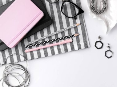 Not defteri, kalem ve kadın aksesuarları olan modern beyaz masa. Üst manzara, ev konseptinden düz döşeme işi