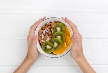 Kadınların elleri portakallı, kivili ve hindistan cevizli mısır gevreği tutuyor.