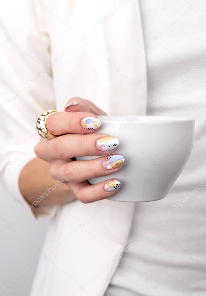 Woman's hand with trendy pastel color nails holding cup. Spring summer nail design. Manicure, pedicure beauty salon concept.