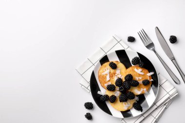 Böğürtlenli hindistan cevizi unundan yapılmış krepler ve beyaz masada hindistan cevizi cipsi. Ev yapımı sağlıklı kahvaltı..