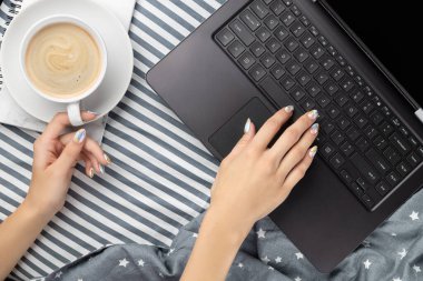 Düz manzaralı çalışma alanı rahat yatak odasında. Yatakta dizüstü bilgisayarda yazı yazan bir kadın eli. Ev kavramından çalış.