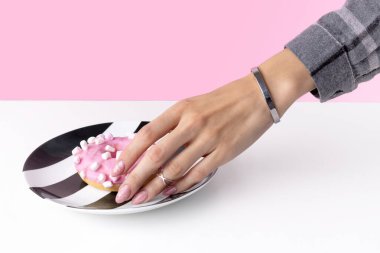 Moda mermer manikürlü, elinde donut olan bir kadın. Pembe bahar yaz tırnak tasarımı. Moda güzellik salonu konsepti