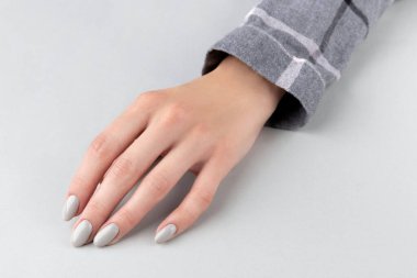 Manikürlü, kareli gömlekli güzel bir kadın eli.