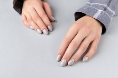 Manikürlü, kareli gömlekli güzel bir kadın eli.