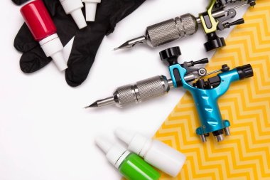 Dövme ustalarının işyeri: dövme makineleri ve beyaz arka planda çeşitli mürekkepler. Kapatın. Dövme sanatçısı stüdyo konsepti.