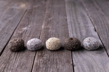 Çiğ enerji topları, eski ahşap arka plandaki doğal malzemelerle hazırlanmış topları ısırır. Sağlıklı gıda vegan tatlıları konsepti