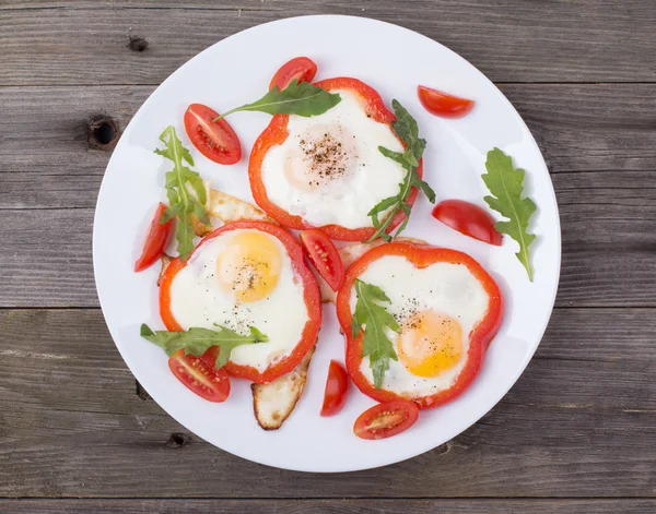 Los huevos en el pimiento en el plato a la mesa — Foto de Stock