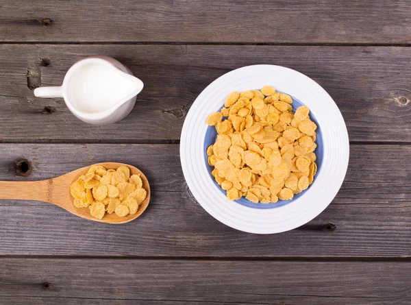Breakfast: flakes in a plate, milk in a jug — Stock Photo, Image