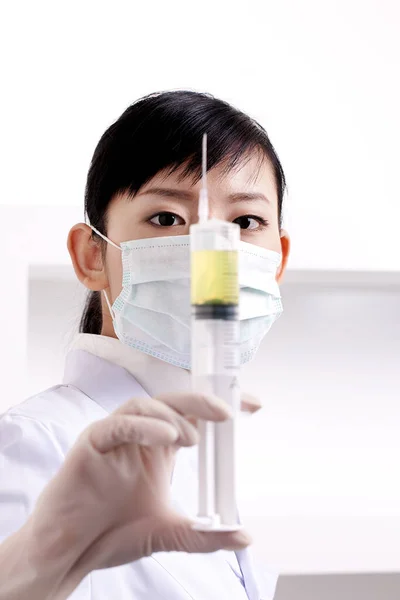 asian woman in medical mask and gloves holding a syringe with a virus